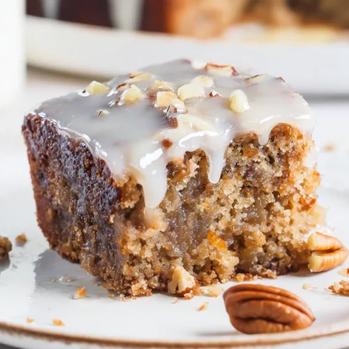 Close-up of a moist, nutty dessert with glossy icing and crunchy praline pieces scattered on top.