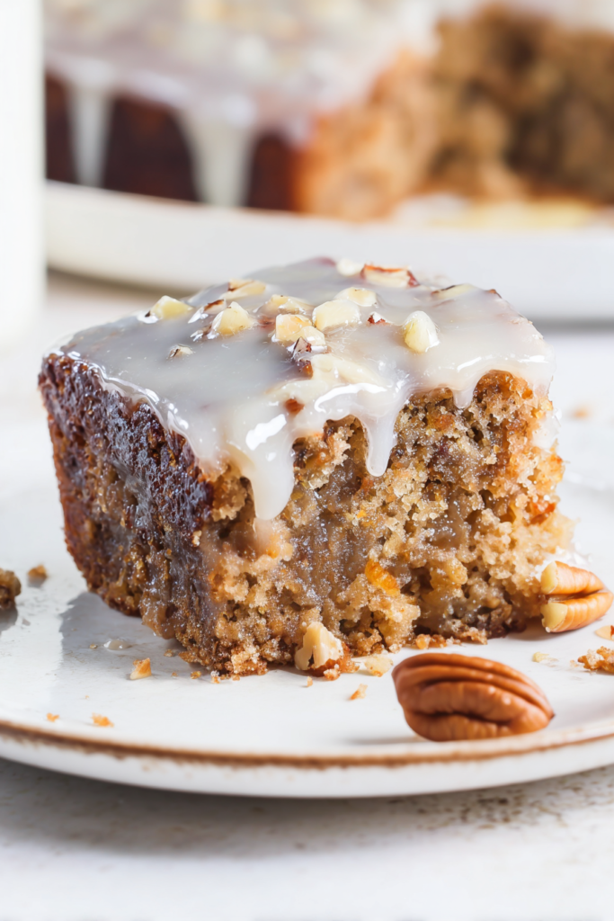 Close-up of a moist, nutty dessert with glossy icing and crunchy praline pieces scattered on top.