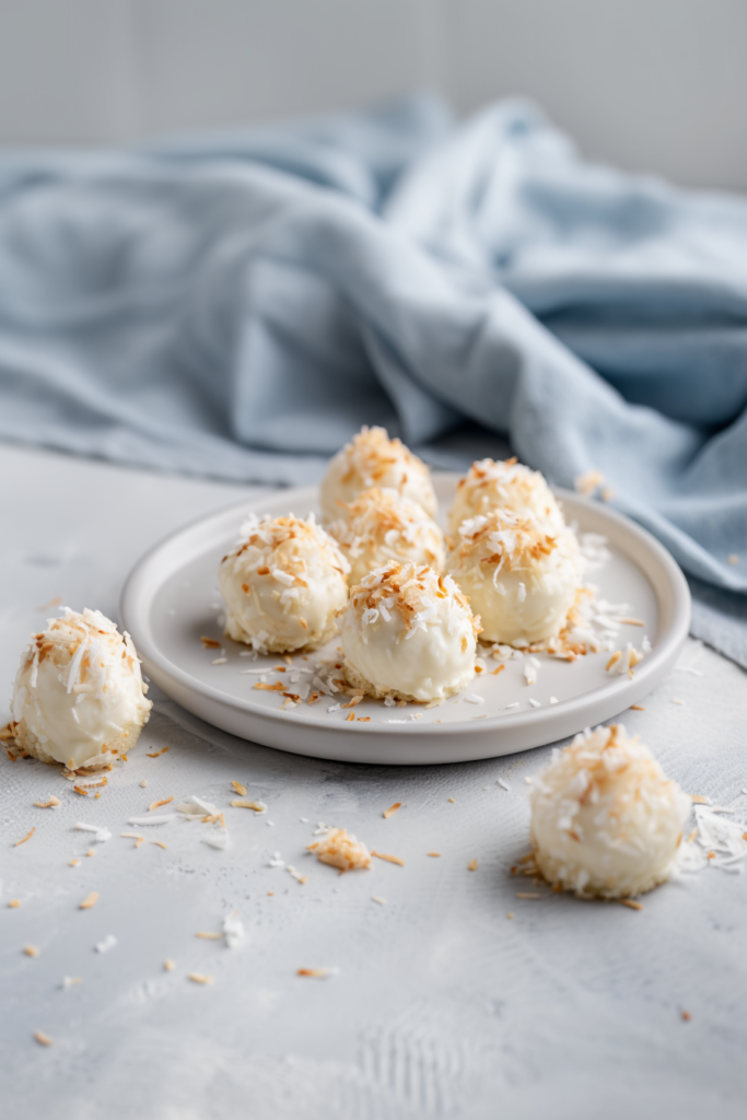 Neatly arranged round treats with golden coconut garnish against a soft blue background