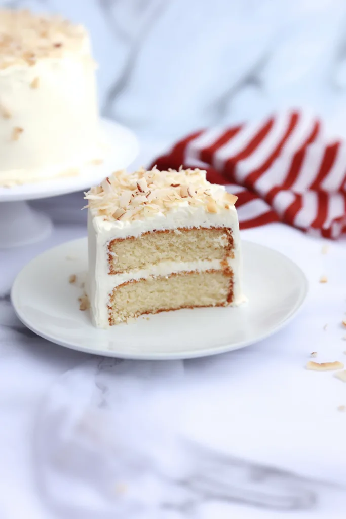 Elegant dessert display featuring a layered cake with coconut flakes, photographed in warm natural light.
