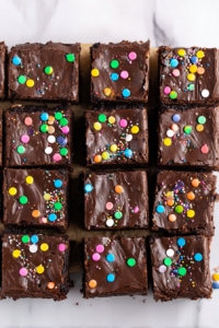 Freshly cut brownies showing fudgy texture, decorated with rainbow sprinkles for a festive look.