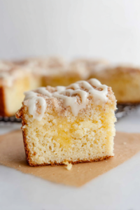 Thick square of homemade breakfast cake with rich cream filling and lemon zest garnish.