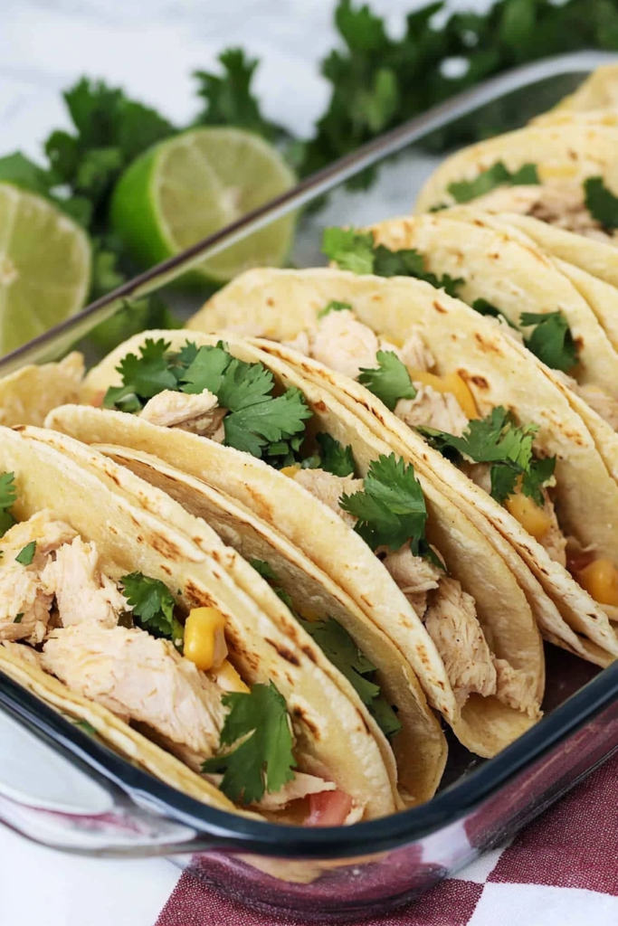 Taco platter featuring juicy chicken, corn, and diced tomatoes with lime garnish.