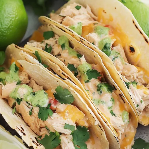 Close-up of baked tacos in a glass dish with golden, cheesy tops.