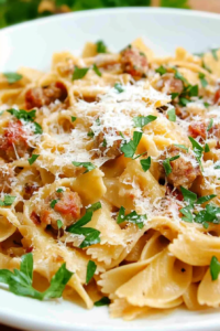 Close-up of farfalle tossed with ground sausage and grated Parmesan.