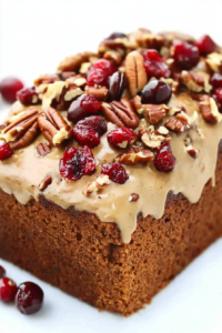 Close-up of a golden brown loaf filled with dried cranberries and scattered nuts.