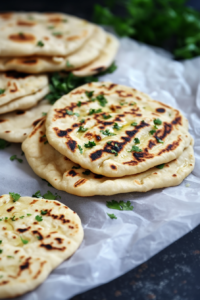 Stacked naan bread with golden grill marks and fresh herbs.