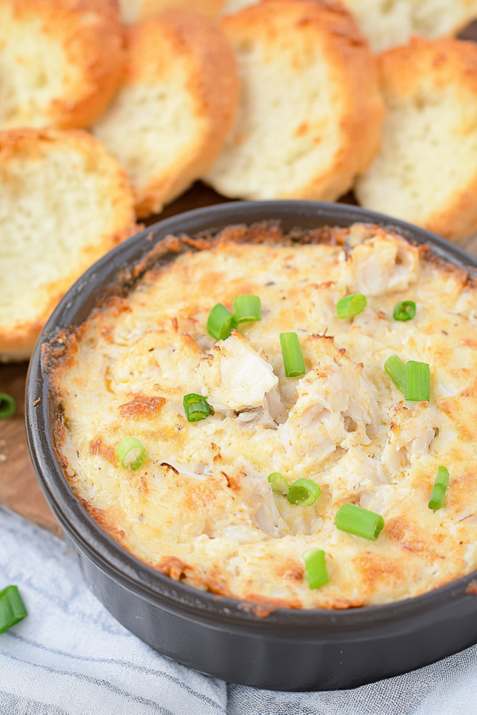Creamy baked crab dip topped with chopped green onions, served with toasted bread rounds.