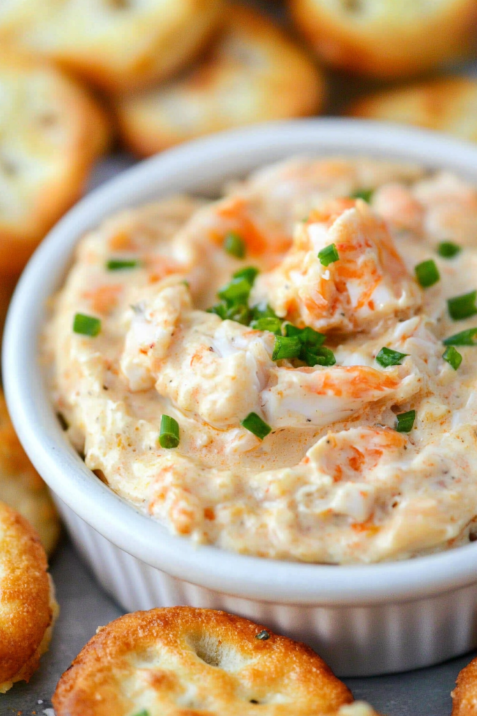 Close-up of warm, cheesy seafood dip with chunks of crab and herbs.