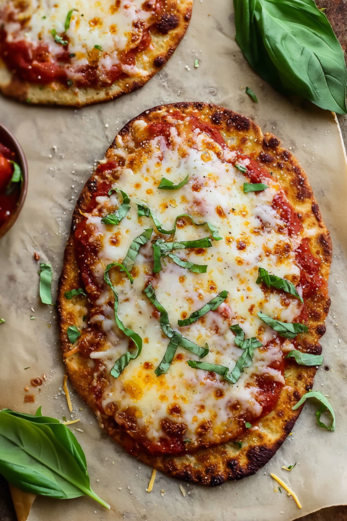 Crispy flatbread topped with melted mozzarella, tomato sauce, and fresh basil leaves