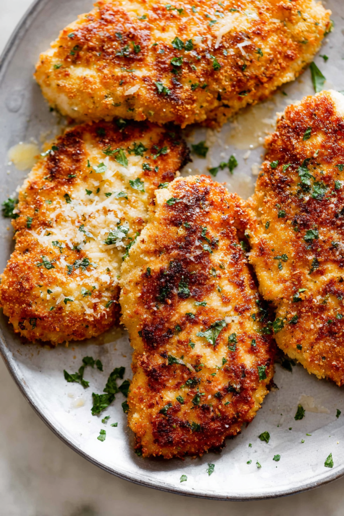 Crispy oven-baked chicken breast with herbs and toasted coating.