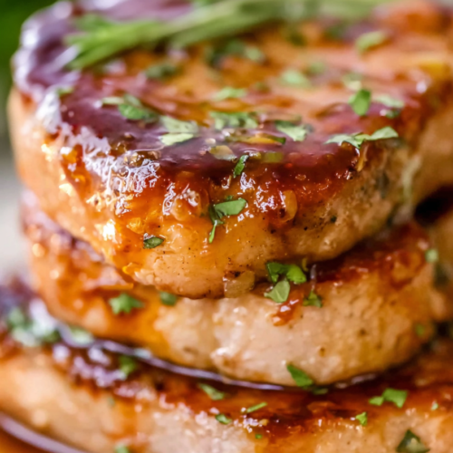 Close-up of caramelized pork chops resting in a rich sauce, finished with sprigs of thyme.