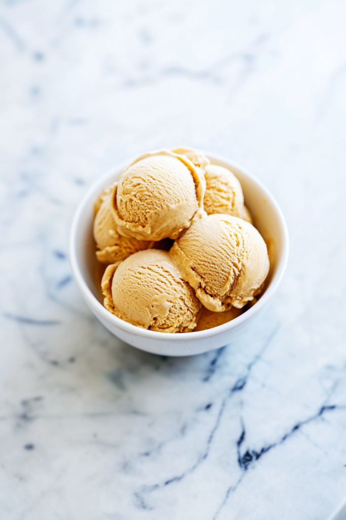 Creamy pumpkin ice cream with gingersnap cookie pieces served in a white bowl.