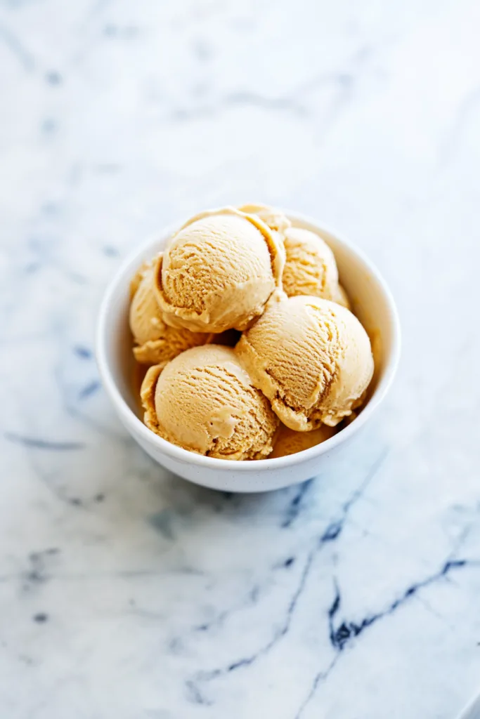 Creamy pumpkin ice cream with gingersnap cookie pieces served in a white bowl.