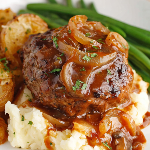Juicy beef steak patty topped with onion gravy served over creamy mashed potatoes with green beans on the side.
