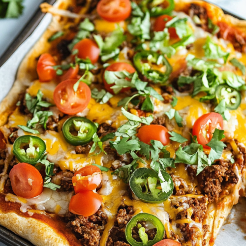 Sheet pan taco pizza cooling after baking, with toppings glistening under warm light.