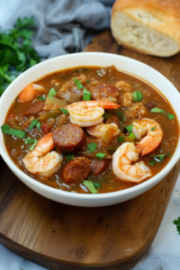 Final dish of gumbo styled for serving, topped with herbs and paired with bread for a comforting meal.