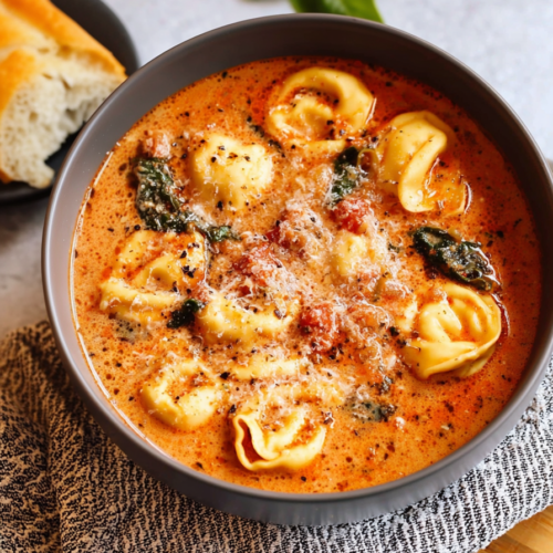 Rustic serving bowl of orange-hued soup garnished with cracked black pepper