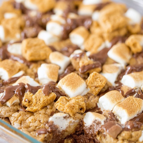 Gooey chocolate and toasted marshmallow bars baked in a glass dish.