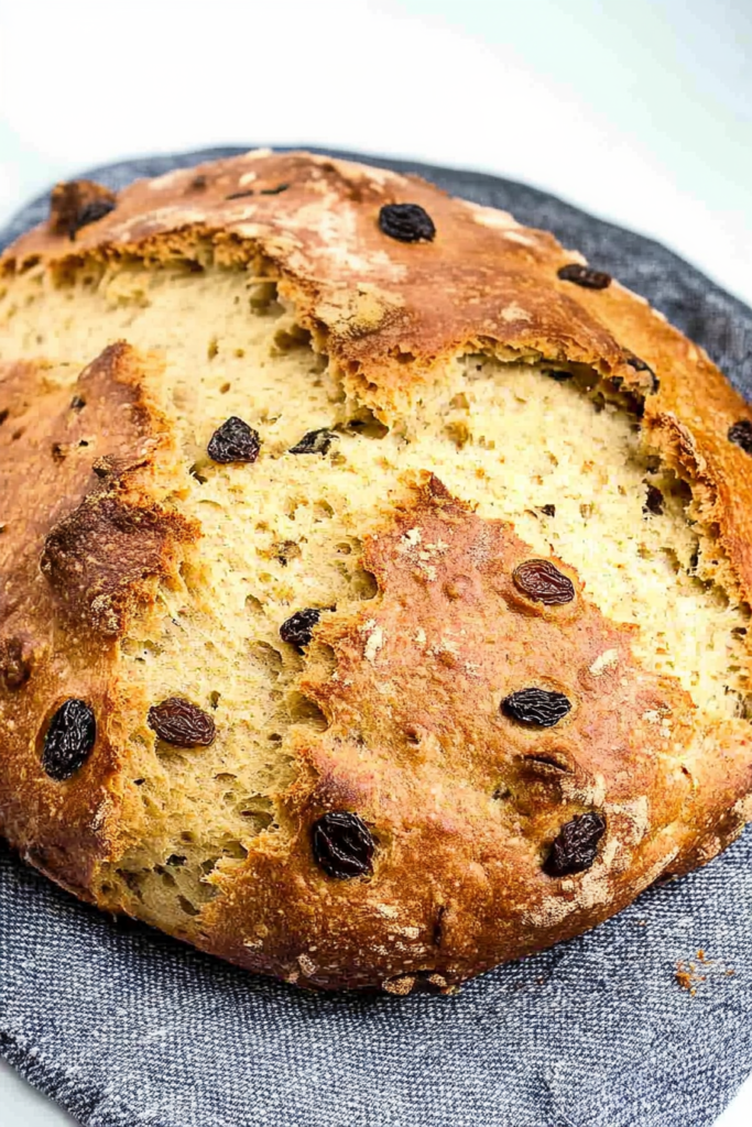 Close-up of sliced bread revealing a soft, fluffy texture with raisins baked into the crust and interior.