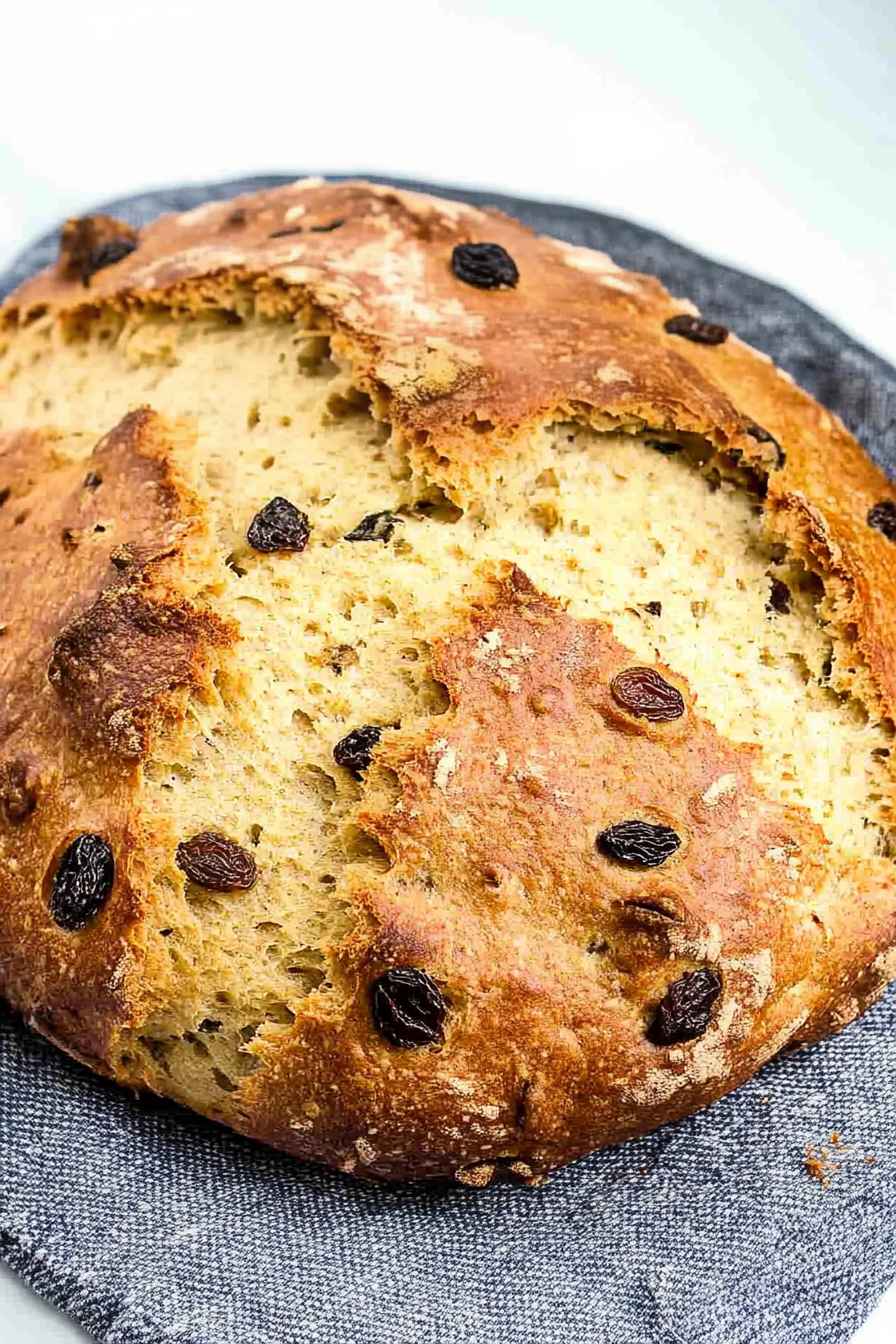 Close-up of sliced bread revealing a soft, fluffy texture with raisins baked into the crust and interior.