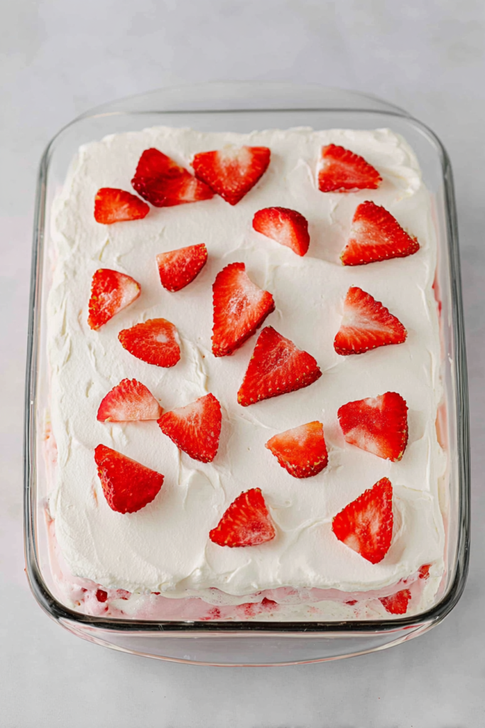 Creamy layered dessert topped with fresh sliced strawberries and whipped cream.