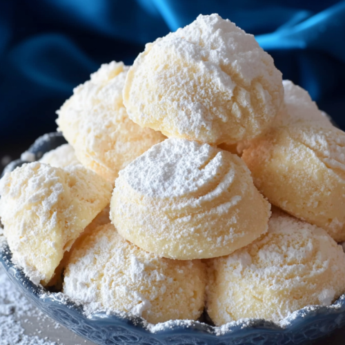 Powdered sugarโcoated soft cookies stacked on a plate, ready to serve.