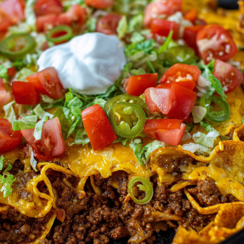 Close-up of layered taco bake with seasoned beef, melted cheese, and crunchy chips.