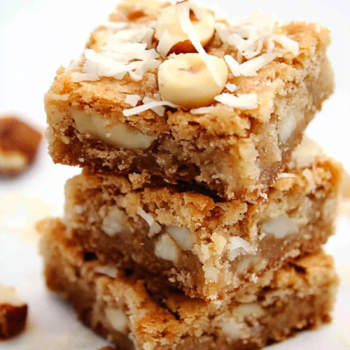 Homemade white chocolate coconut blondies cut into squares and stacked for serving.