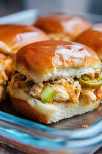 Glossy golden buns filled with shredded chicken, tangy pickles, and a drizzle of sauce.