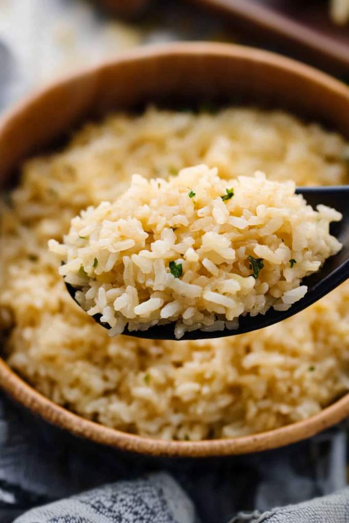 Close-up of fluffy rice with light buttery sheen, served in a dark ceramic bowl