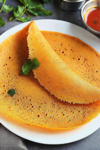 Crispy golden dosa folded on a plate with a light, lacy texture