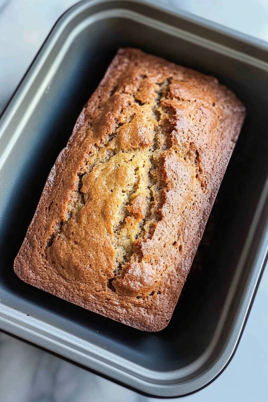 Freshly baked banana bread loaf, cut to display dense crumb and natural sweetness.