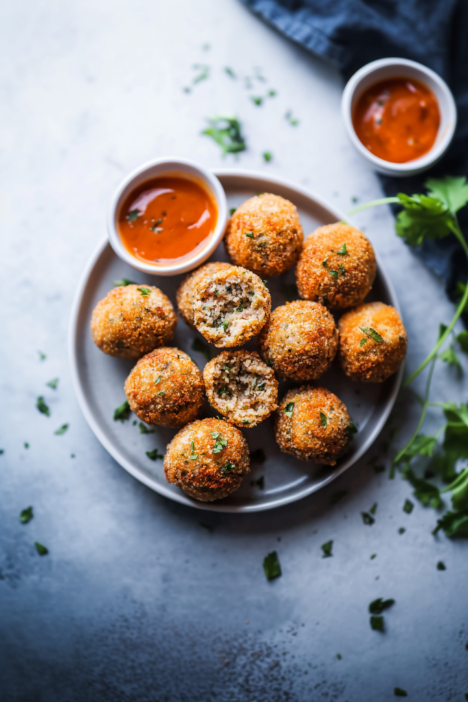 Crispy breaded boudin balls garnished with fresh herbs, styled simply with a rustic background.