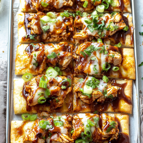 Crispy flatbread pieces arranged neatly, each slice loaded with barbecue chicken chunks and vibrant toppings.
