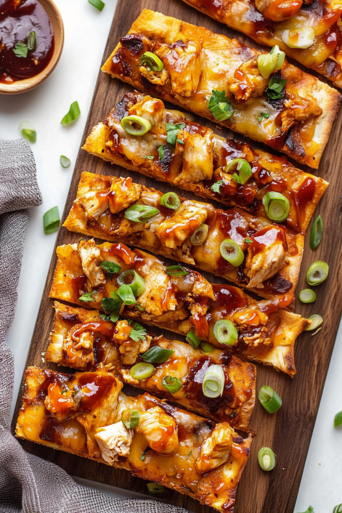 Golden flatbread pizza cut into portions, layered with smoky chicken, gooey cheese, and garnished with cilantro and green onions.