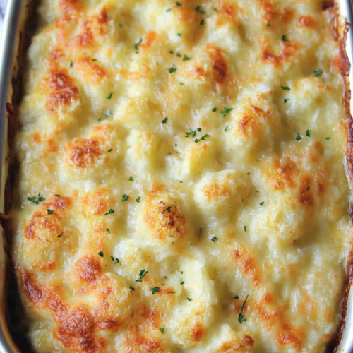 Freshly baked dish showcasing melted cheese over tender cauliflower, garnished with sprigs of thyme.