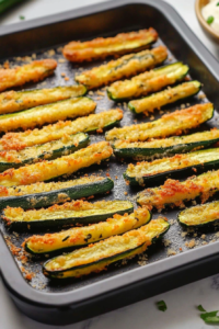 Crispy oven-roasted zucchini fries topped with grated parmesan and fresh herbs.