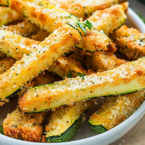 Bowl of crunchy baked zucchini sticks with a cheesy breadcrumb coating.