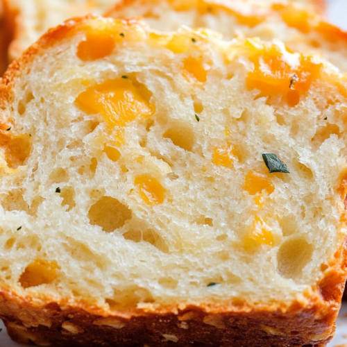 Thick slices reveal a soft, cheesy interior with herbs scattered across the golden crust.