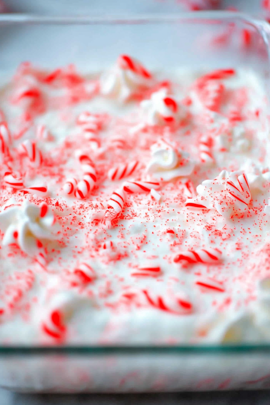 Close-up of a fluffy peppermint cream dessert square with crushed candy canes.