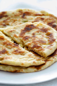 Close-up of pan-fried bread with toasted spots and creamy potato-cheese mixture peeking through.