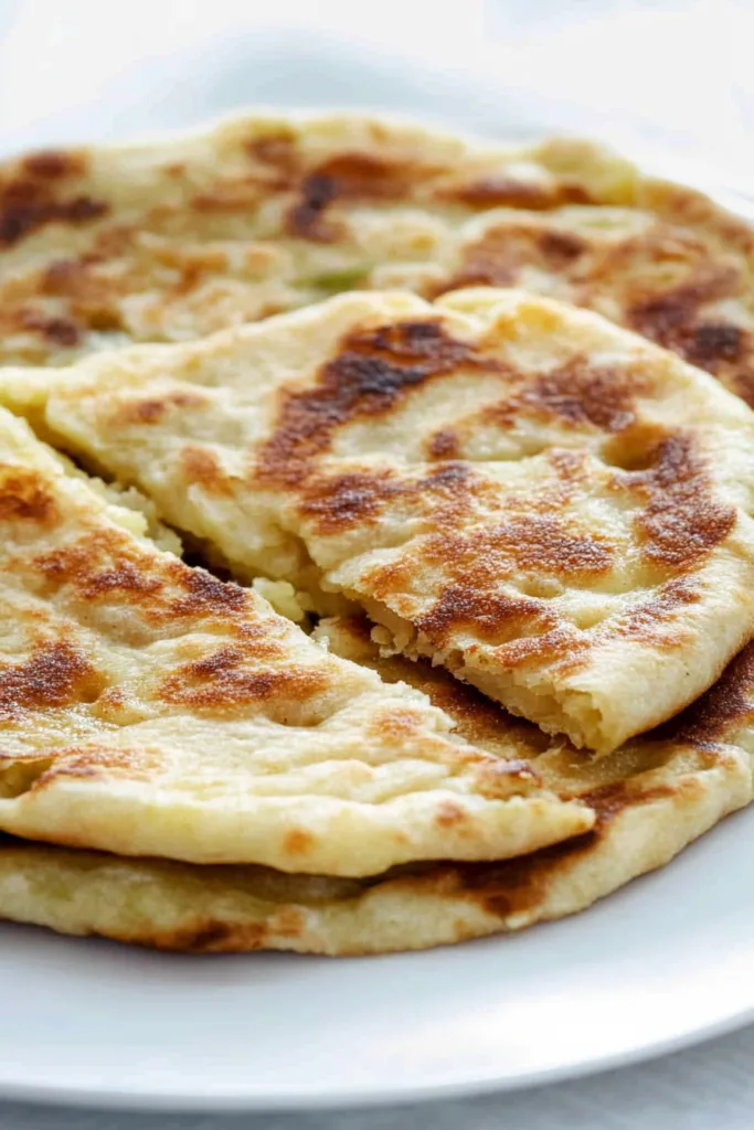 Close-up of pan-fried bread with toasted spots and creamy potato-cheese mixture peeking through.