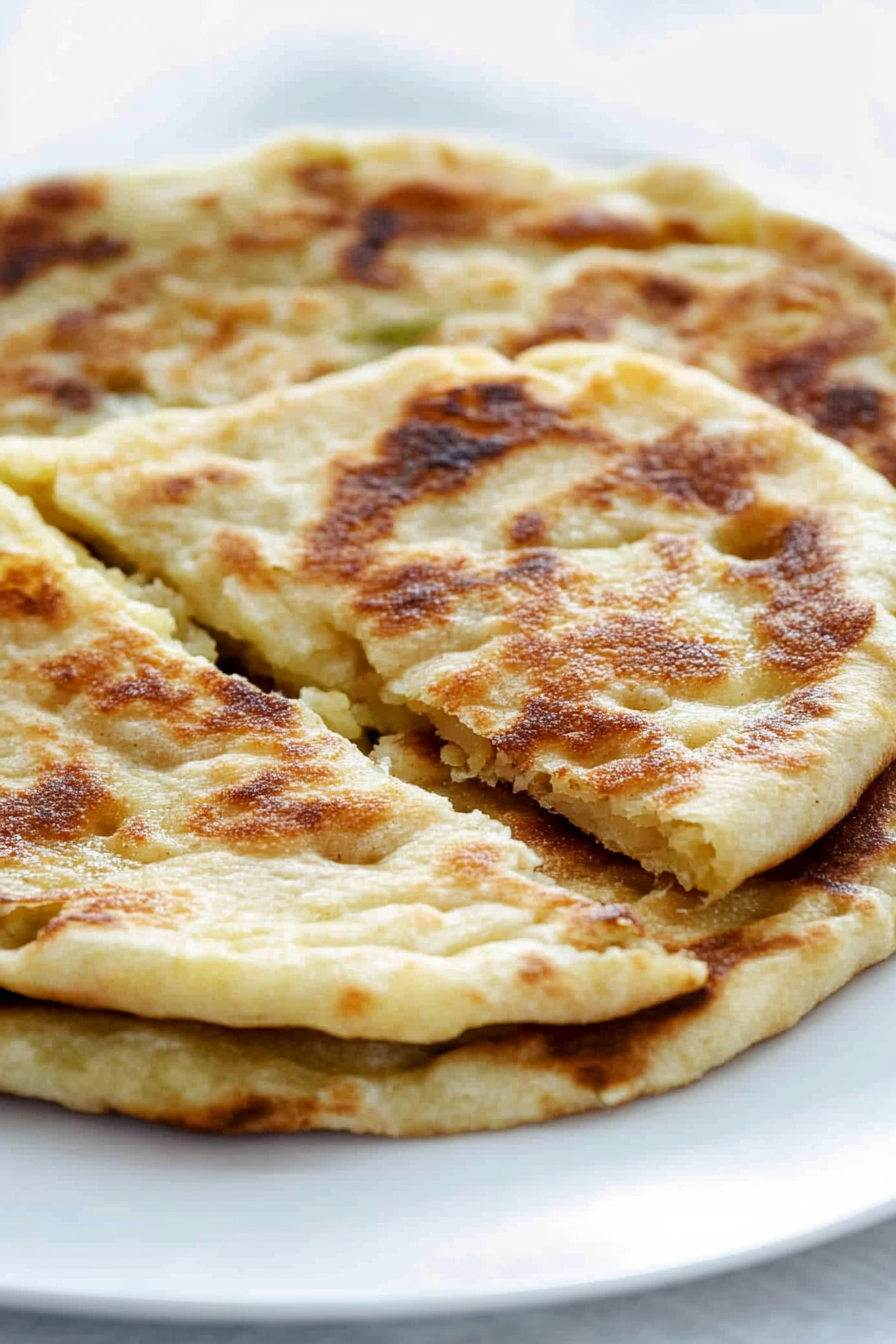 Close-up of pan-fried bread with toasted spots and creamy potato-cheese mixture peeking through.