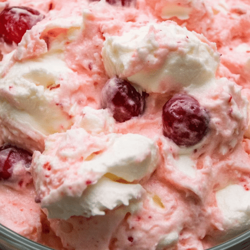 Close-up of the fluffy dessert showing cherries nestled in the smooth, pastel pink mixture.