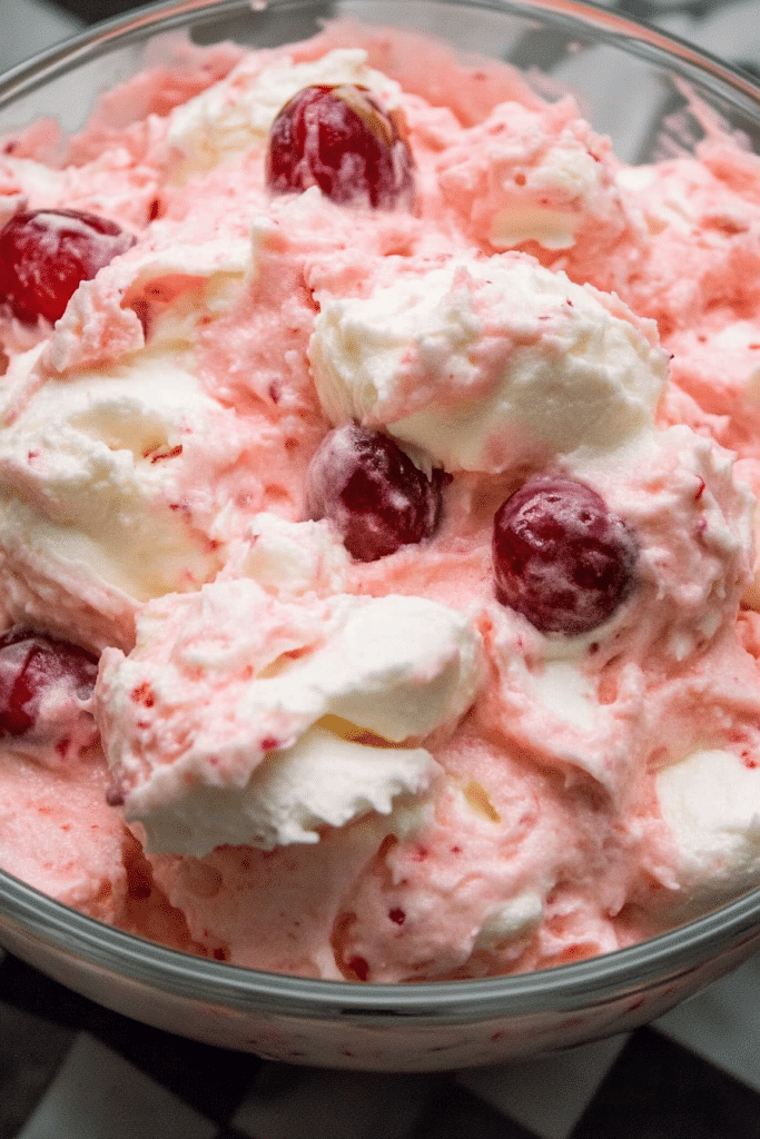 Close-up of the fluffy dessert showing cherries nestled in the smooth, pastel pink mixture.