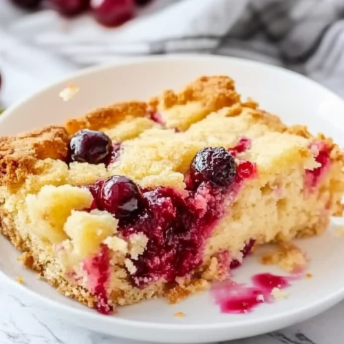 Slice of warm cobbler-style cake on a plate, highlighting the moist fruit center.