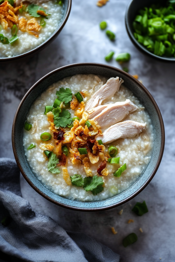 Final dish of rice porridge styled simply, with tender chicken and crunchy shallots on top.
