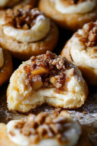 Batch of baked buns topped with cinnamon crumble and chopped nuts, lightly dusted with sugar.
