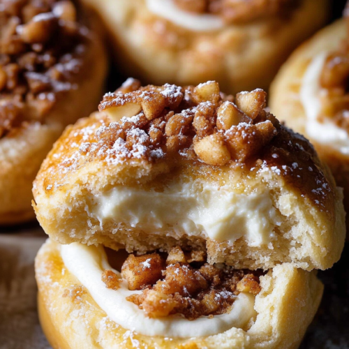 Close-up of golden pastry showing apple pieces, crumb topping, and dusting of powdered sugar